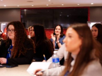 Student sitting among others in a conference room on clapping their hands and smiling